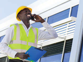 Workers in safety gear discussing a project over the phone
